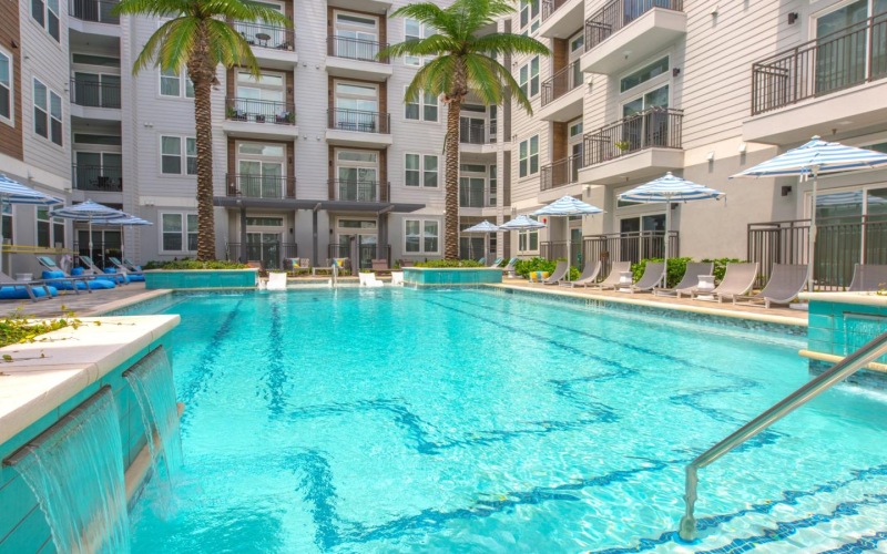 pool with reclining seats and lush landscaping
