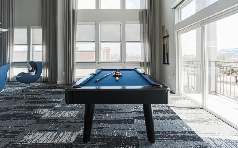 a pool table in a room with ample lighting from large windows